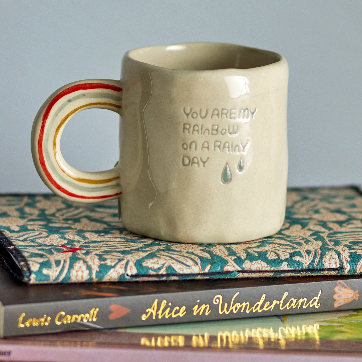 Photograph of the cloudy mug on top of and Alice in Wonderland book.