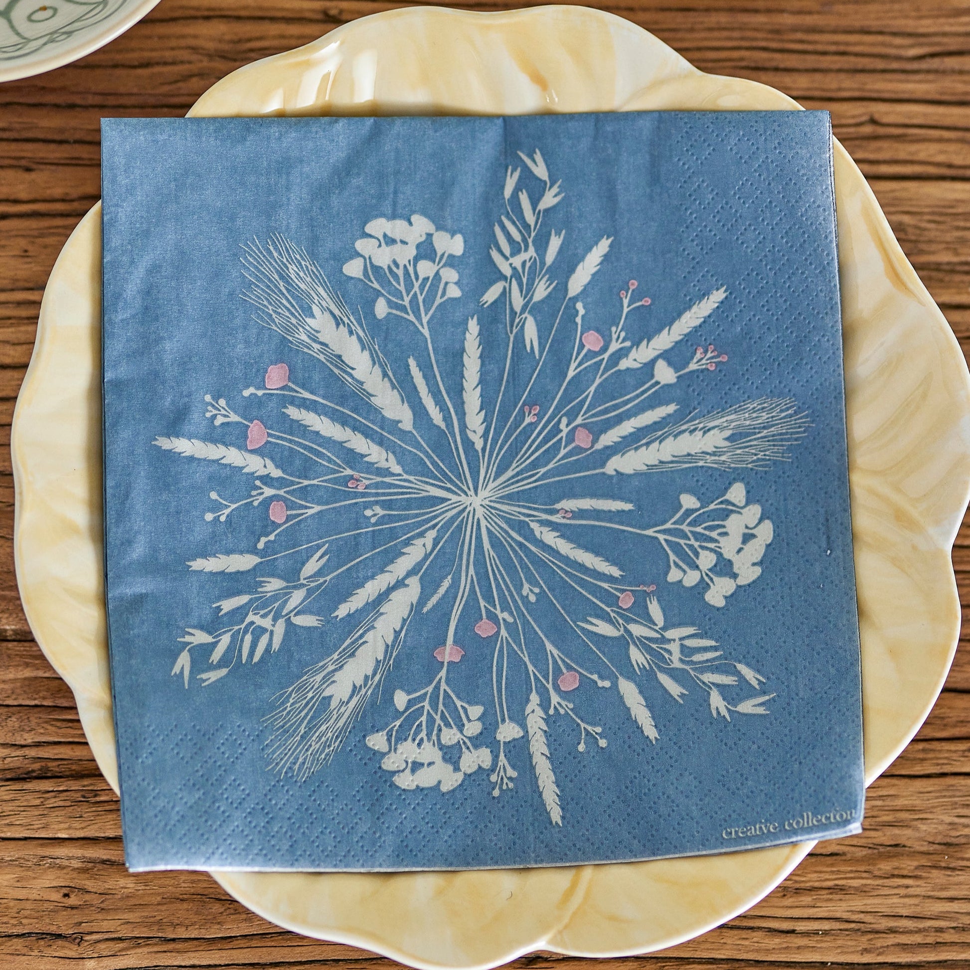 Blue napkin with floral detail on a pale yellow plate