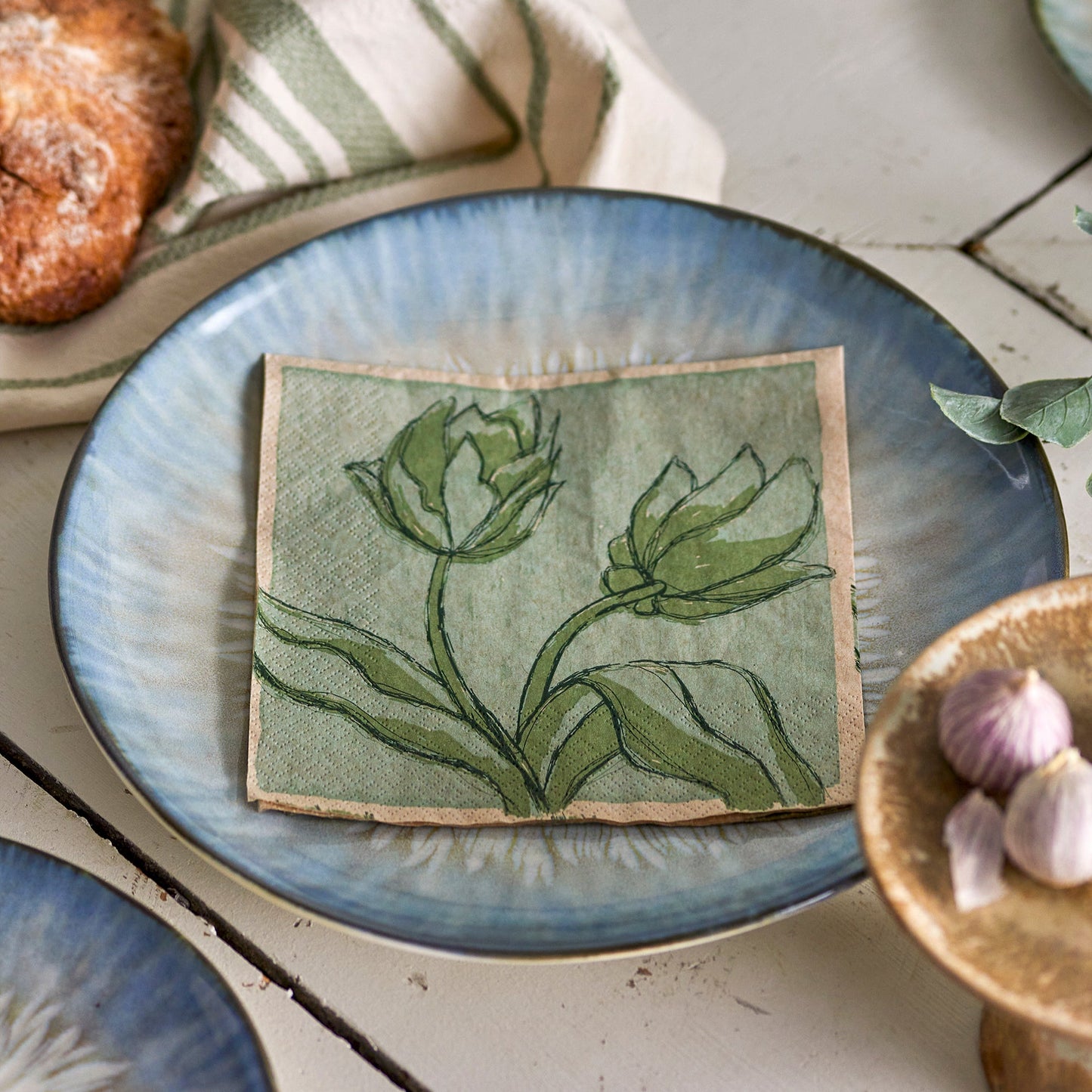 Green floral napkins, on a blue plate. Photographed on a bust tablescape. 