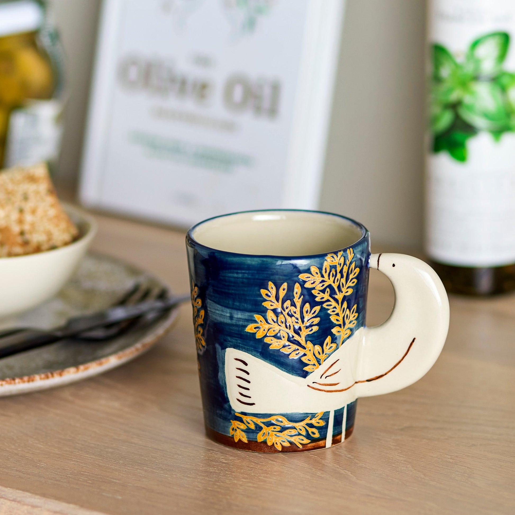 Blue mug with bird handle on a table setting.