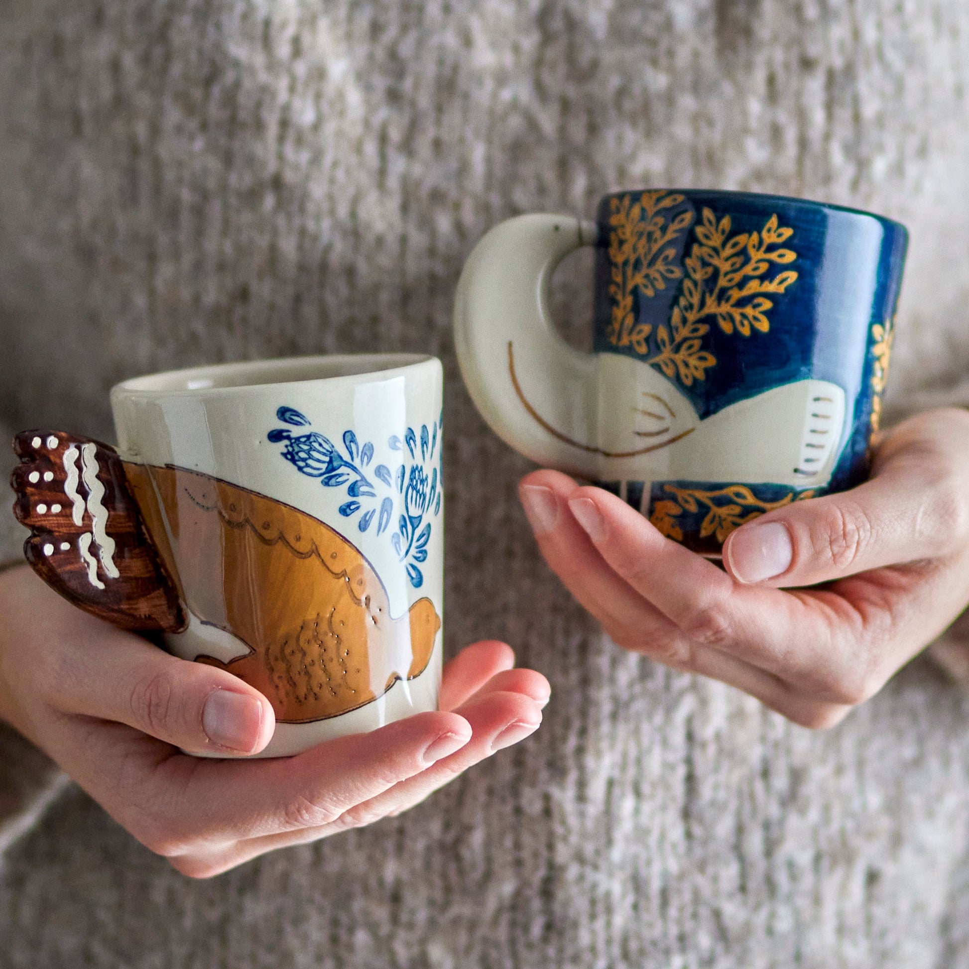 Mugs being held in a person's hands.