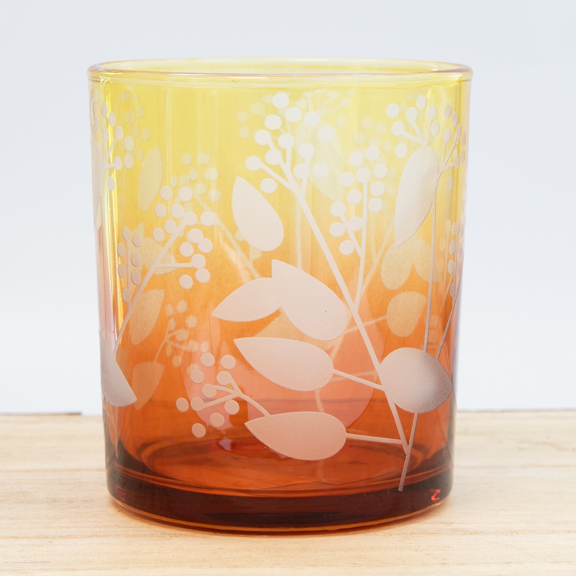 Glass tumbler with floral design on a wooden surface