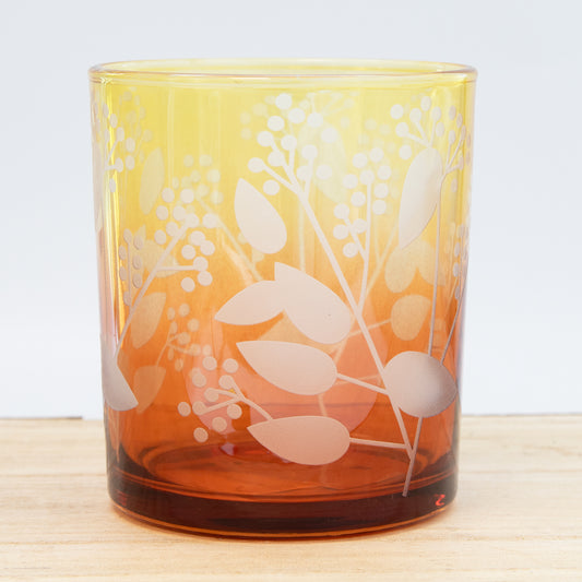Glass tumbler with floral design on a wooden surface