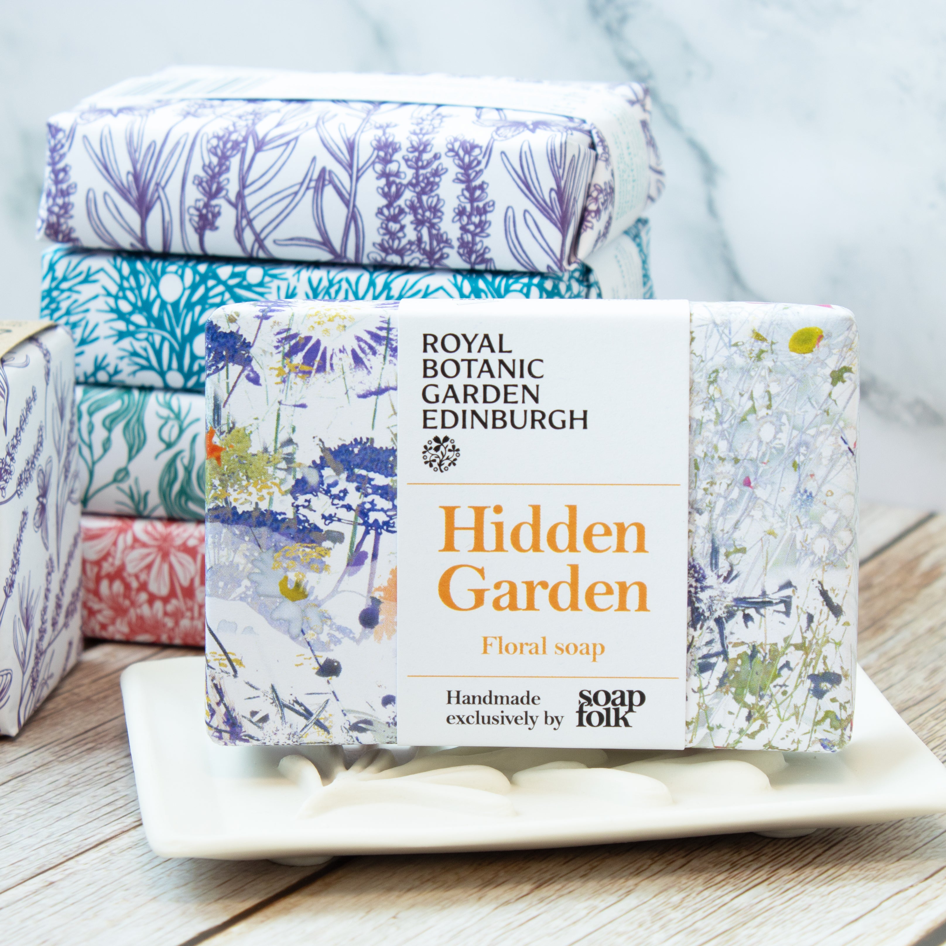 Soap bars with floral packaging and 'Royal Botanic Garden Edinburgh' branding on a wooden surface.